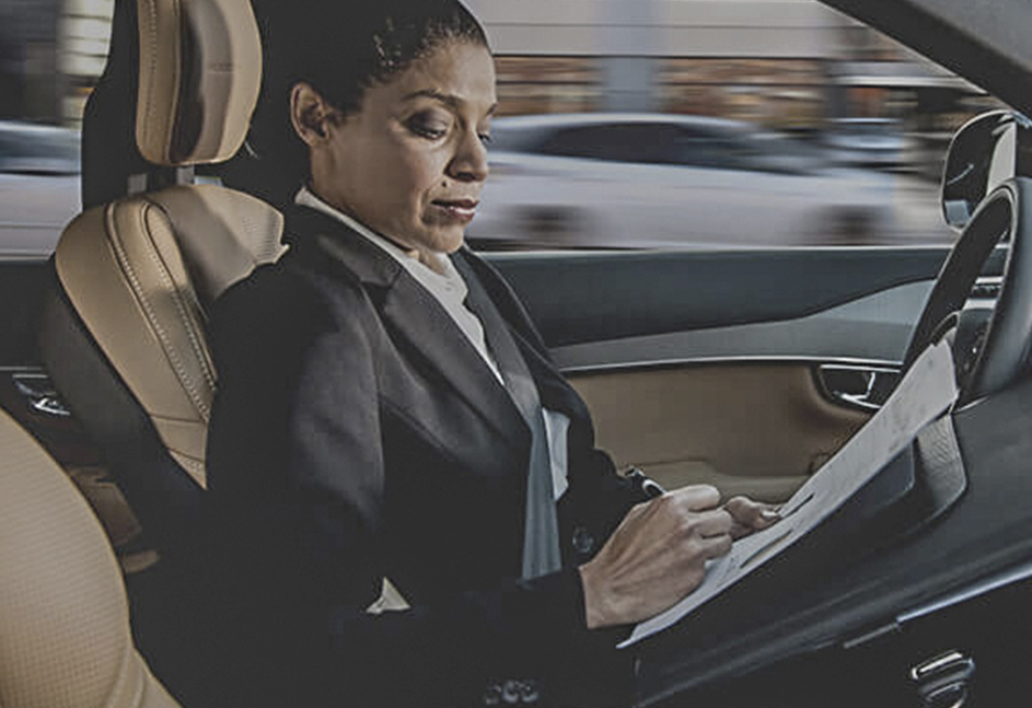 Woman in self-driving vehicle doing paperwork while driving